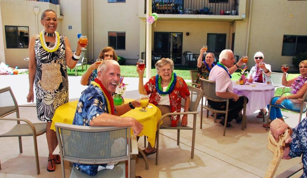 A group of seniors enjoying an outdoor party with drinks and leis.