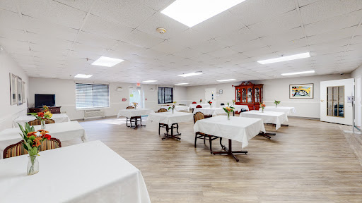 A spacious event room set up with white tablecloths and wooden flooring, ready for gatherings or meetings.
