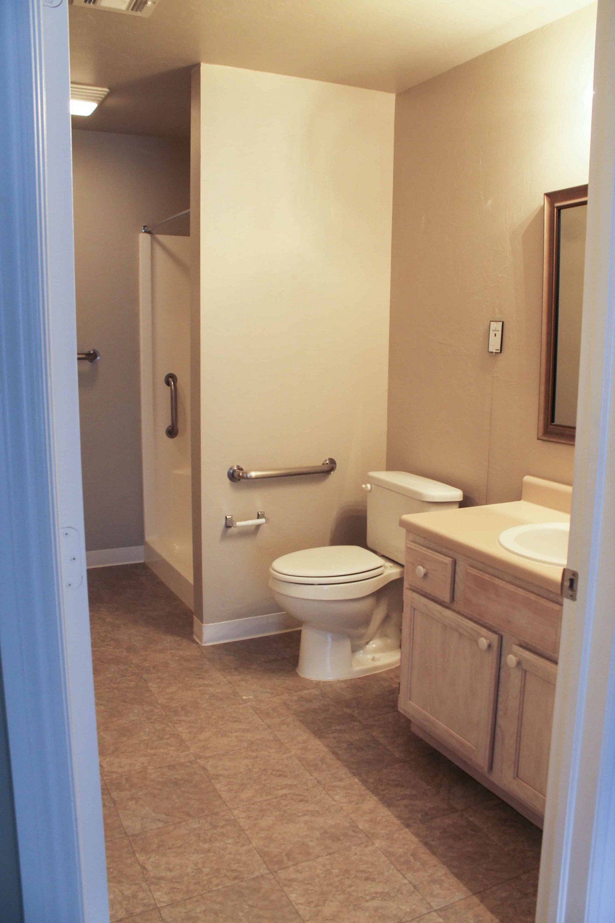 A well-lit bathroom with a toilet, sink, and shower area.