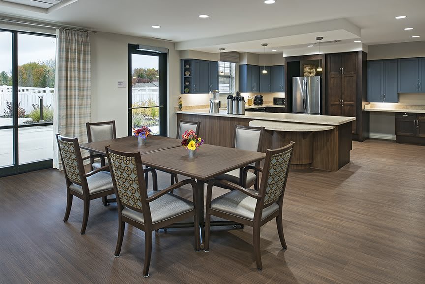 A modern kitchen with a dining area featuring a wooden table and chairs on wood flooring.