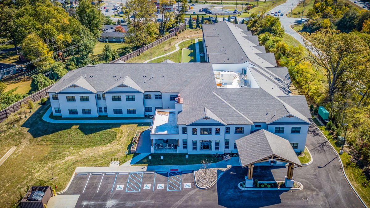 Aerial view of a large building complex with a parking lot and surrounding greenery.