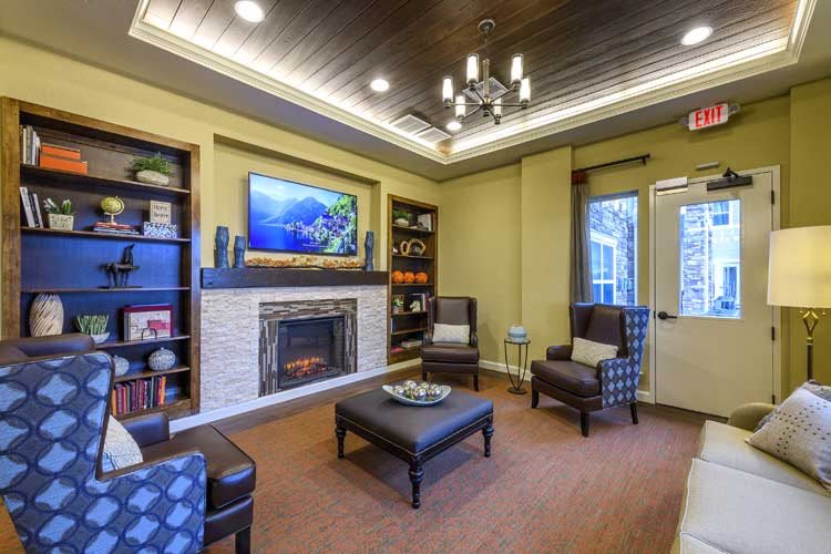A modern living room with a fireplace, comfortable seating, and a wall-mounted television.