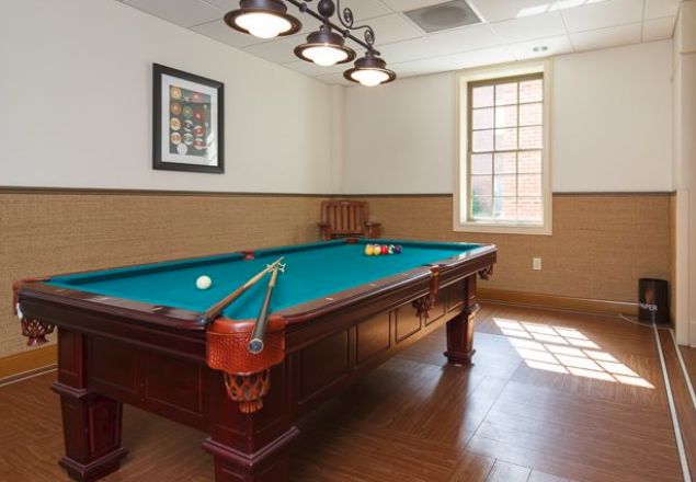 A well-lit game room featuring a billiards table with cues and balls ready for play.