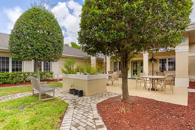 A beautifully landscaped backyard with a patio featuring outdoor seating and a brick pathway.