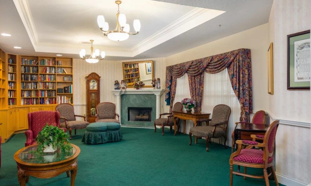 A cozy living room with traditional decor, featuring a fireplace, bookshelves, and comfortable armchairs.