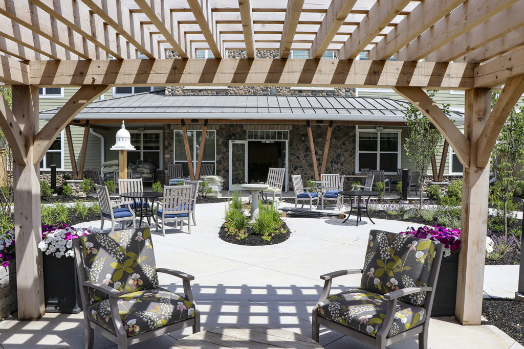 A sunny courtyard with outdoor seating and a pergola overhead.