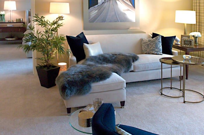 A cozy living room featuring a stylish sofa adorned with a faux fur throw, surrounded by modern decor and a potted plant.