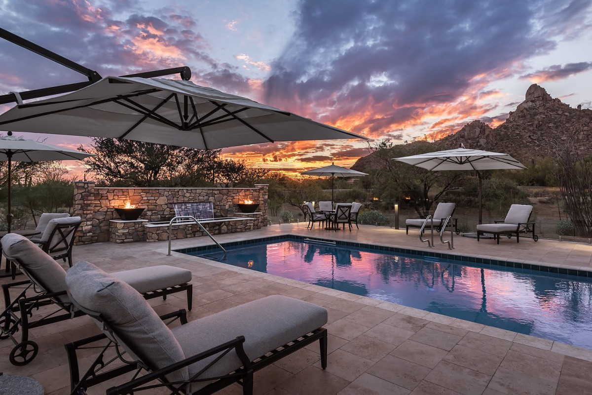 A serene patio with a pool under a stunning sunset sky.