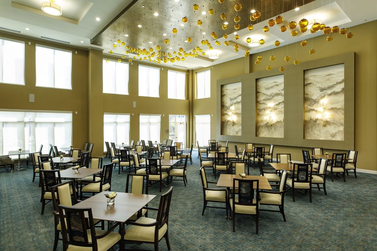 A spacious and elegant dining area with neatly arranged tables and chairs under a modern ceiling design.