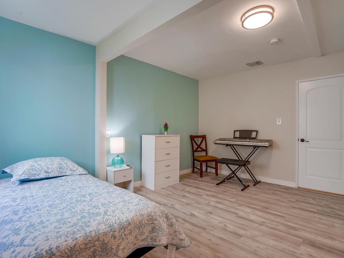 A cozy bedroom with a bed, dresser, and a small desk area.
