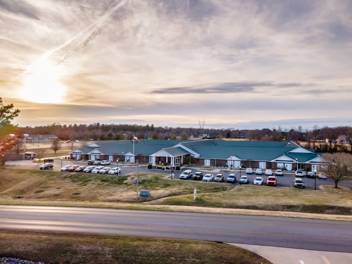 A scenic view of a large building with a parking lot at sunset.