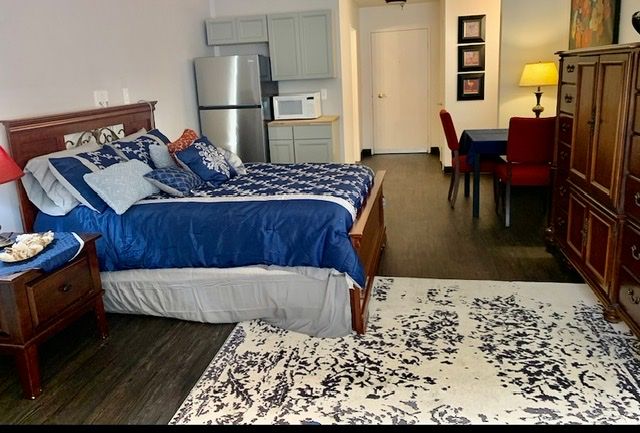 A modern studio apartment with a bed, small kitchen area, and dining table.