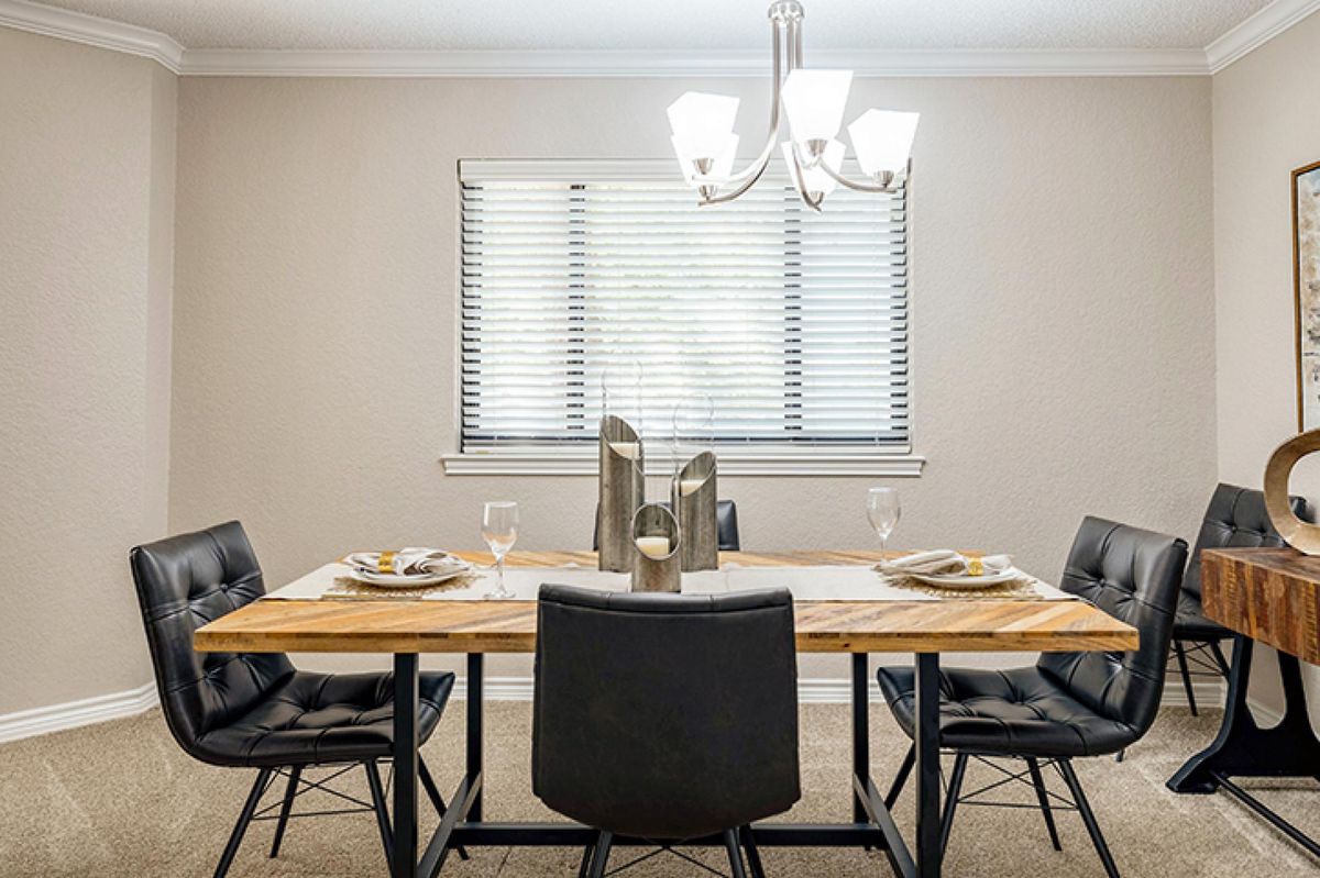 A dining room with a wooden table set for a meal, featuring black chairs and a modern chandelier.