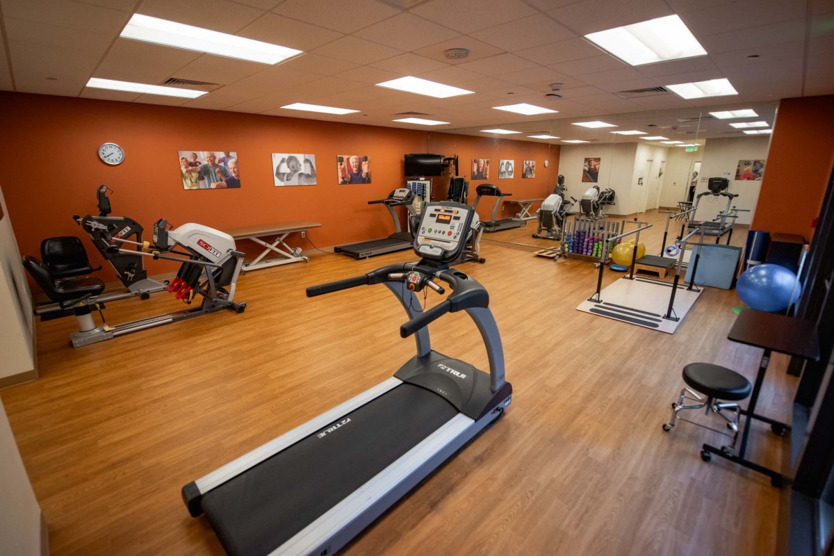A well-equipped gym with various exercise machines, including a treadmill.