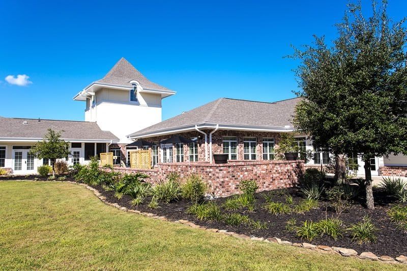 A charming residential building with a well-maintained garden under a clear blue sky.