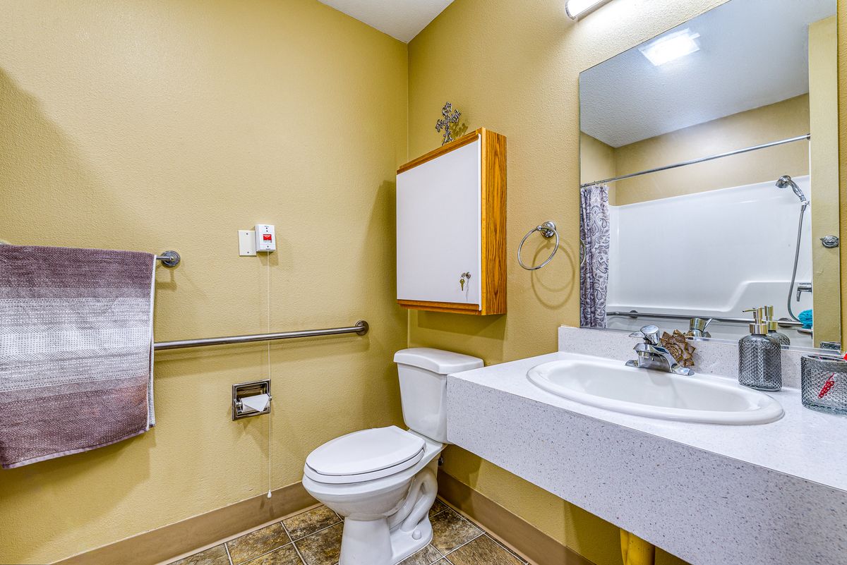 A bathroom featuring a toilet, sink, mirror, and storage cabinet.
