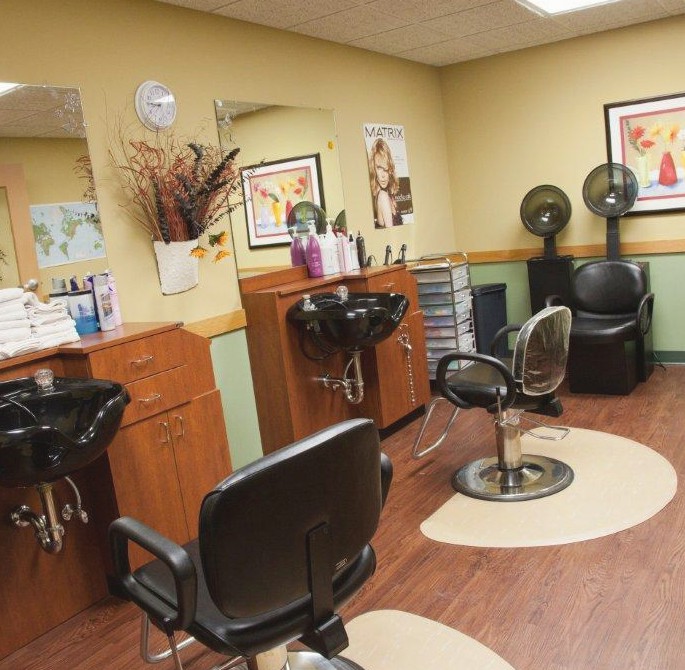 An empty hair salon with chairs and hairdressing stations.