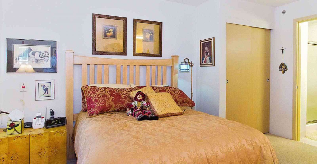 A cozy bedroom with decorative pillows and framed artwork.