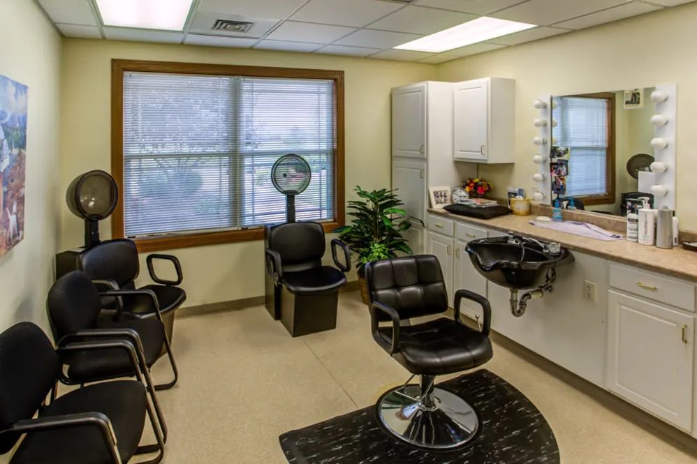 An empty hair salon with styling chairs and a mirror.