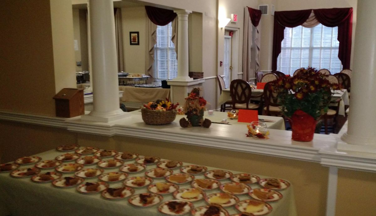 A cozy dining area with autumn-themed decorations and a table filled with assorted desserts.
