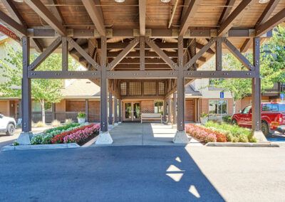 The entrance of a building with wooden beams and manicured landscaping.