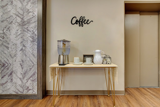 A stylish coffee station featuring a sleek table, decorative items, and a refreshing beverage dispenser.