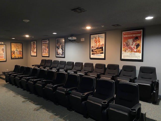 A cozy home theater with multiple rows of seating and movie posters on the walls.