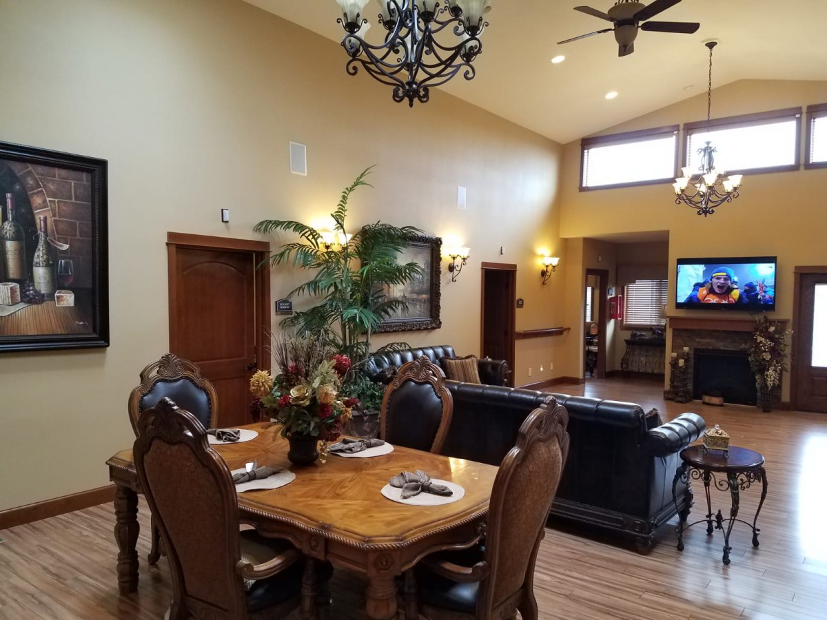 Spacious living and dining area with elegant wooden furniture, chandeliers, and a cozy seating arrangement.