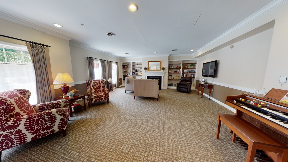 A spacious living room featuring comfortable seating, a fireplace, and bookshelves.