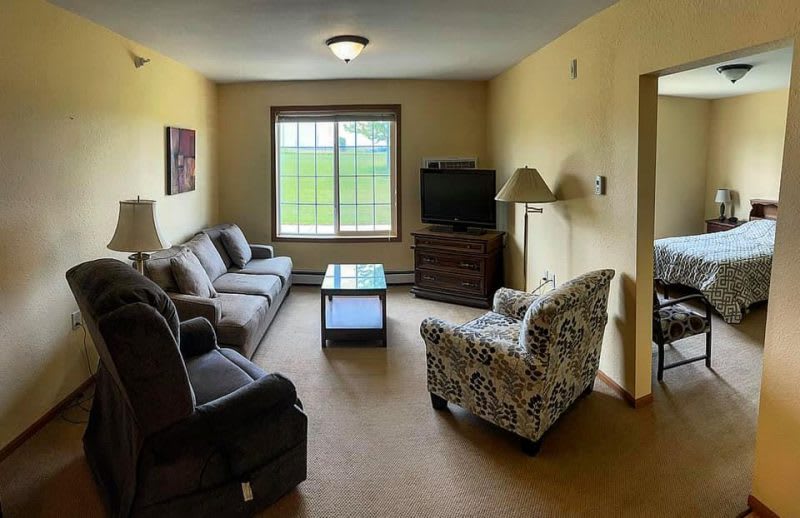 A cozy living room with a sofa, armchair, coffee table, and television.