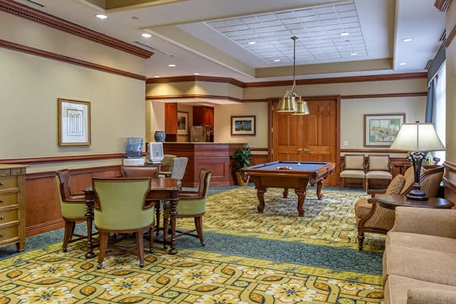 A cozy recreation room featuring a billiards table, seating area, and warm lighting.