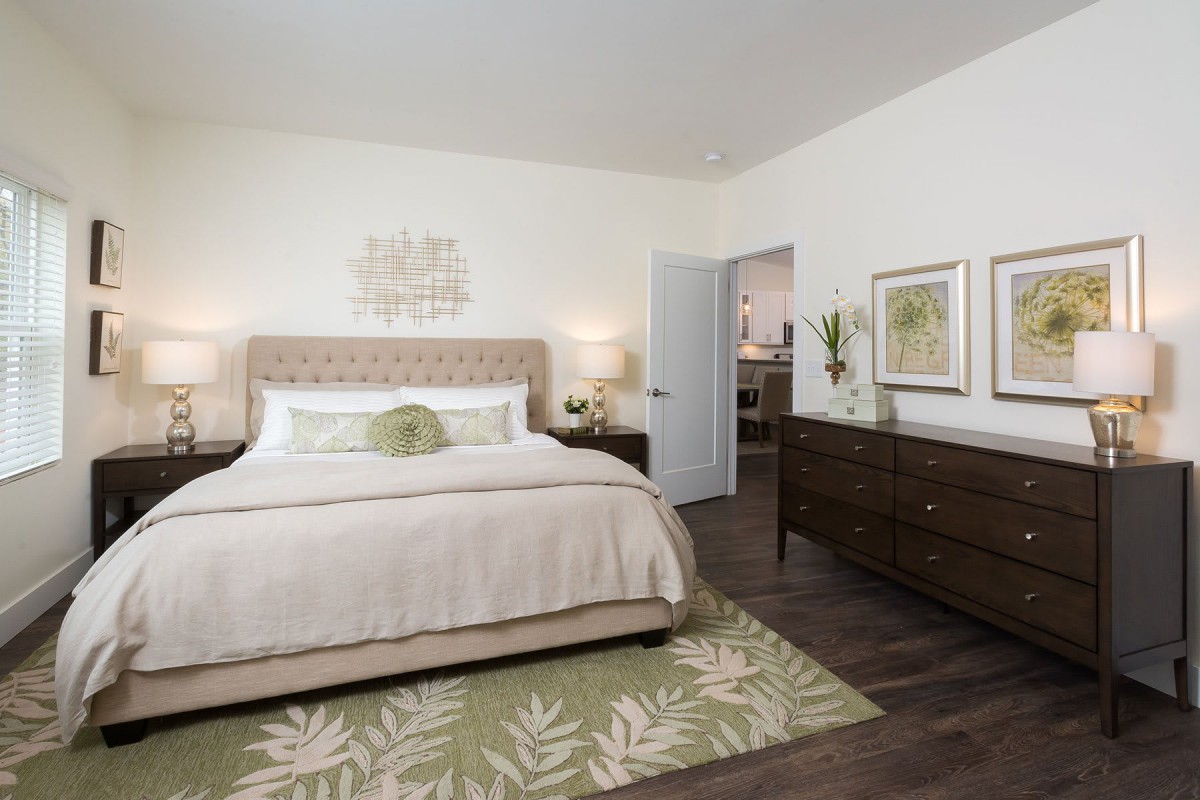 A modern bedroom with a large bed, decorative pillows, a patterned rug, and stylish furniture.