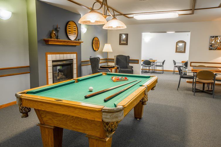 A cozy game room featuring a pool table and a fireplace.