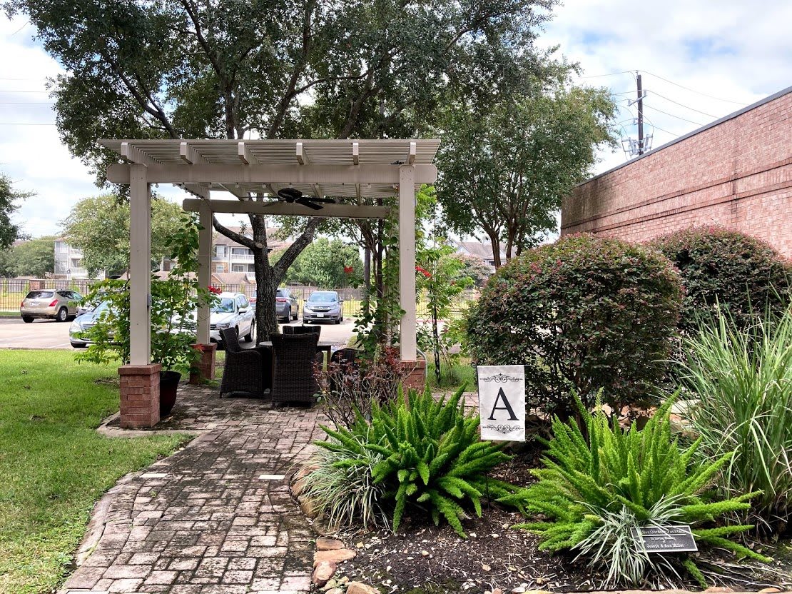 A serene garden setting featuring a pergola, lush greenery, and a cobblestone pathway.
