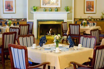 An elegantly set dining room with a cozy fireplace in the background.