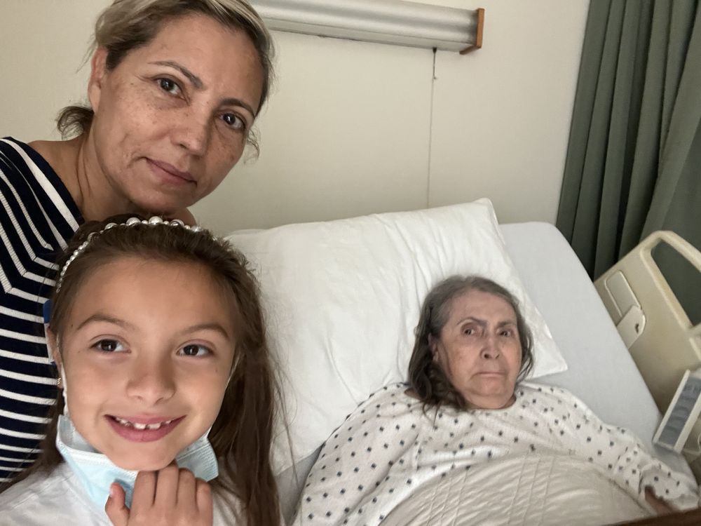 A woman and a child visiting an elderly woman in a hospital bed.