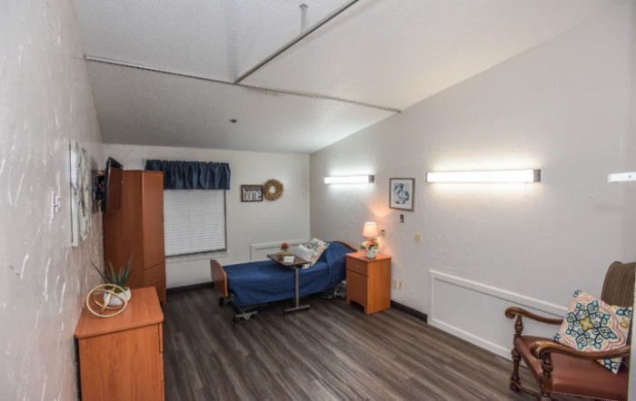 A clean and organized hospital room with a single bed, bedside table, and basic decor.