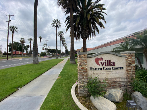 Entrance to Villa Health Care Center, surrounded by palm trees and a scenic pathway.