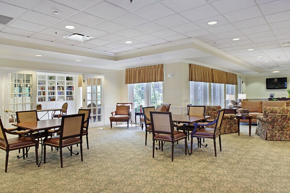 A spacious dining area with multiple tables and chairs, well-lit by natural light from large windows.