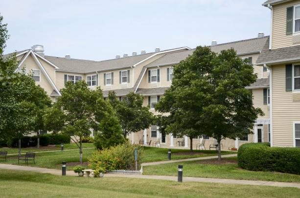A residential apartment complex surrounded by landscaped greenery and trees.