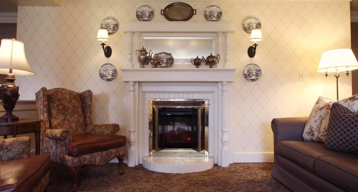 A cozy living room with a traditional fireplace, decorated with wall plates and sconces.