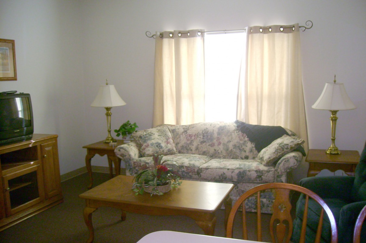 A cozy living room with a floral sofa, wooden coffee table, and soft lighting.