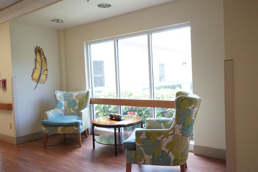 A cozy corner with patterned chairs and a small table, illuminated by natural light from the large windows.