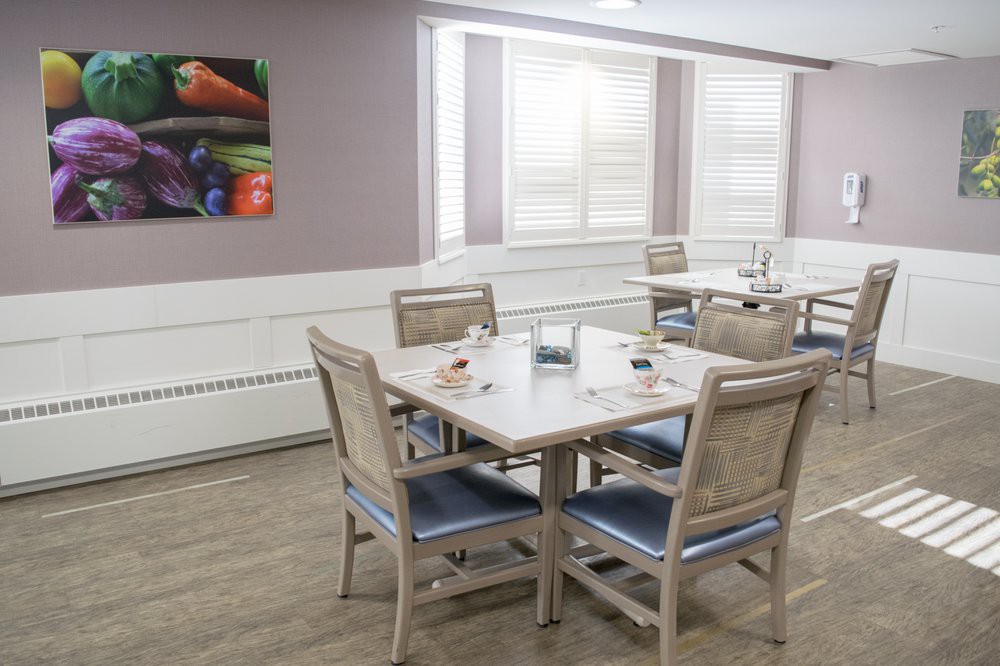 A modern dining area featuring a neatly set table with four chairs and colorful artwork on the wall.