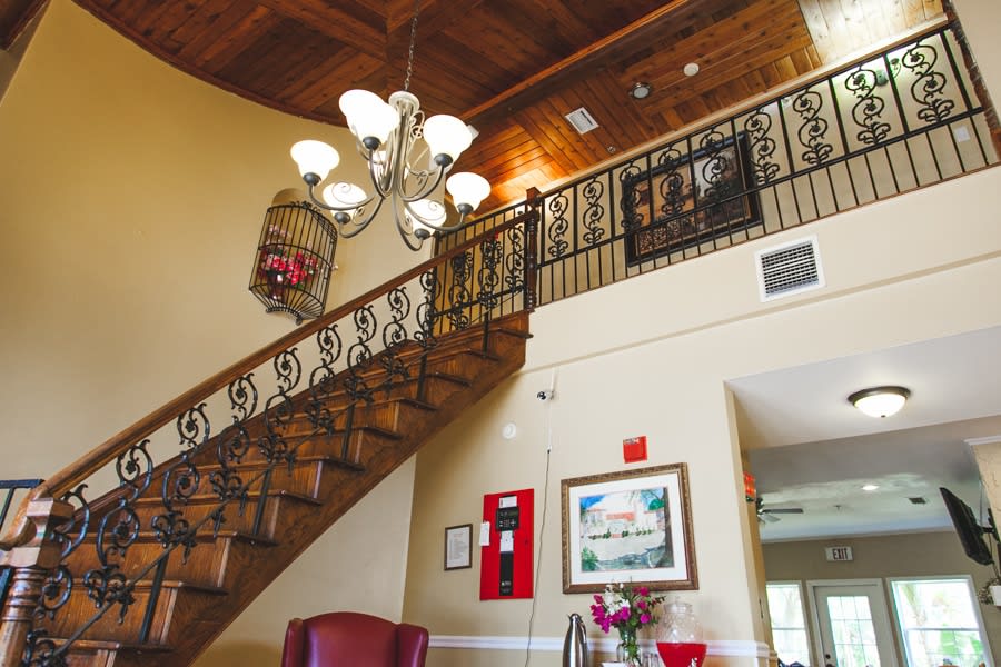 Elegant interior featuring a staircase with ornate railing and a chandelier.