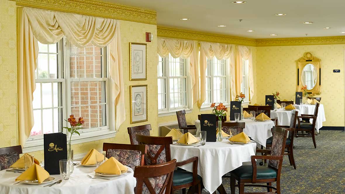 A cozy restaurant dining area with elegantly set tables and yellow decor.