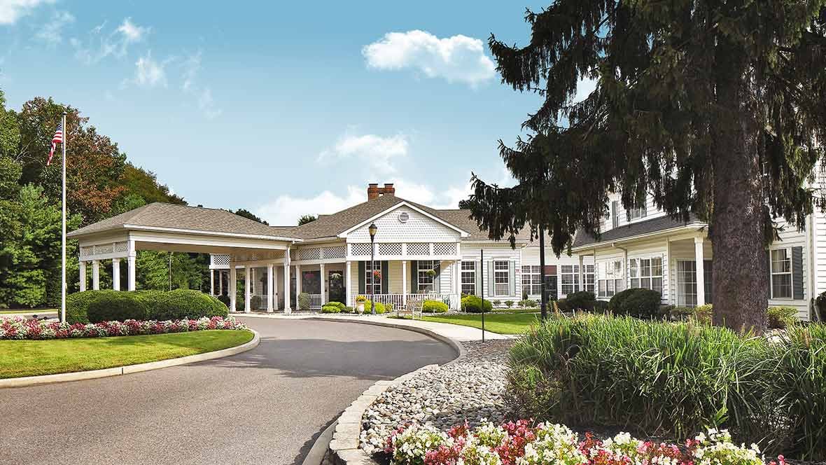 A picturesque residential building with a landscaped garden and circular driveway.
