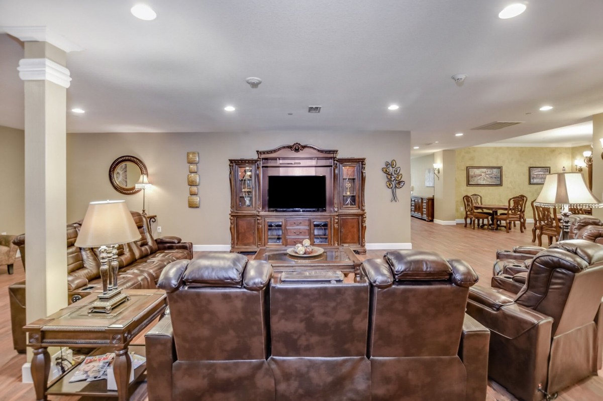 A cozy living room with leather sofas facing a large entertainment unit and television.
