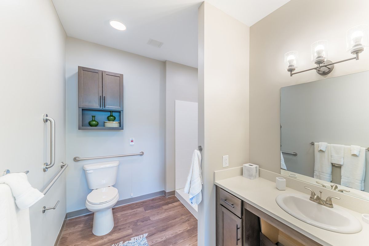 A modern bathroom with a sleek design, featuring a toilet and sink with a mirror above the countertop.