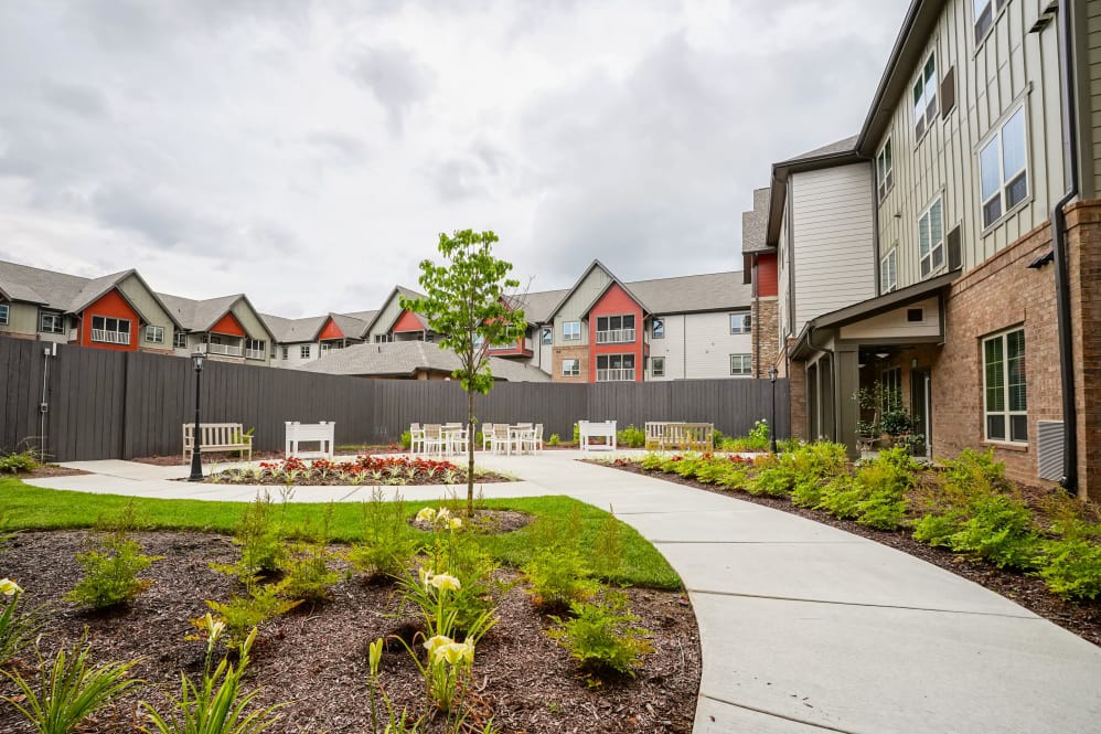 A scenic view of a landscaped garden with a winding pathway, surrounded by modern residential buildings.